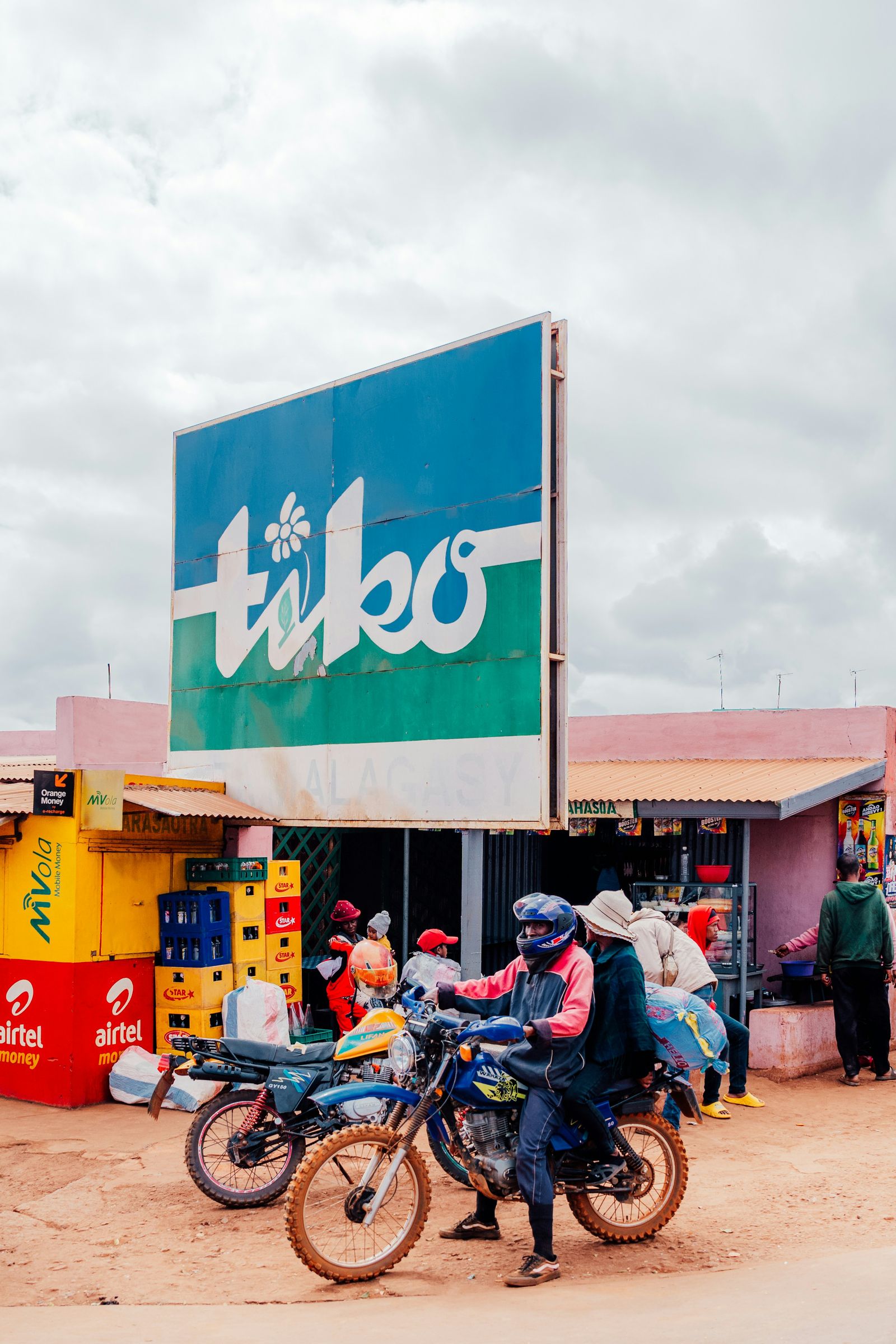 Motorbikes outside a roadside shop with MVola, Airtel Money and Orange Money kiosks, in the Antananarivo area