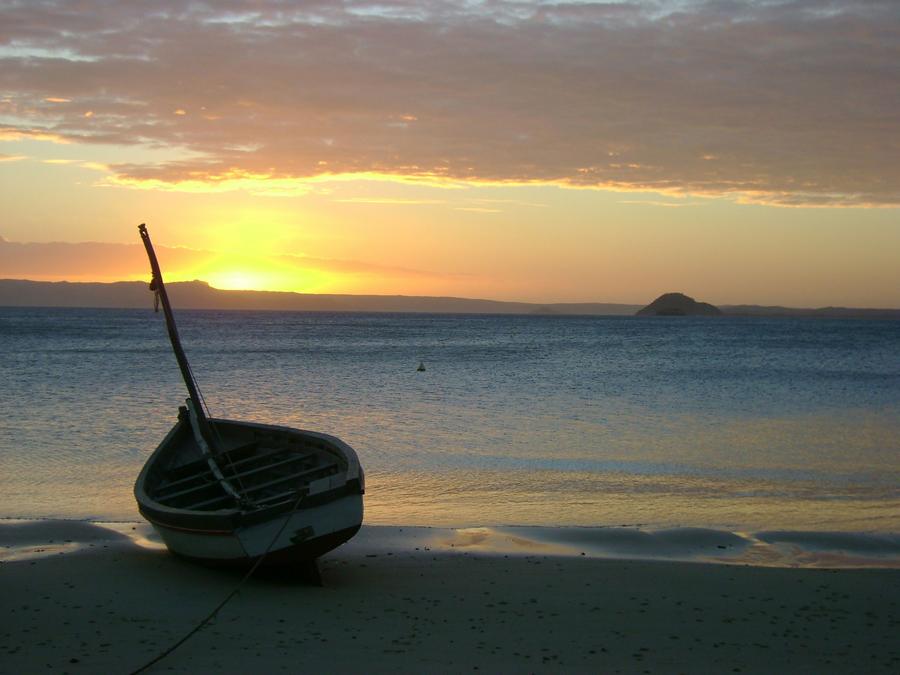 A wooden boat pulled up on a beach at sunset in northern Madagascar