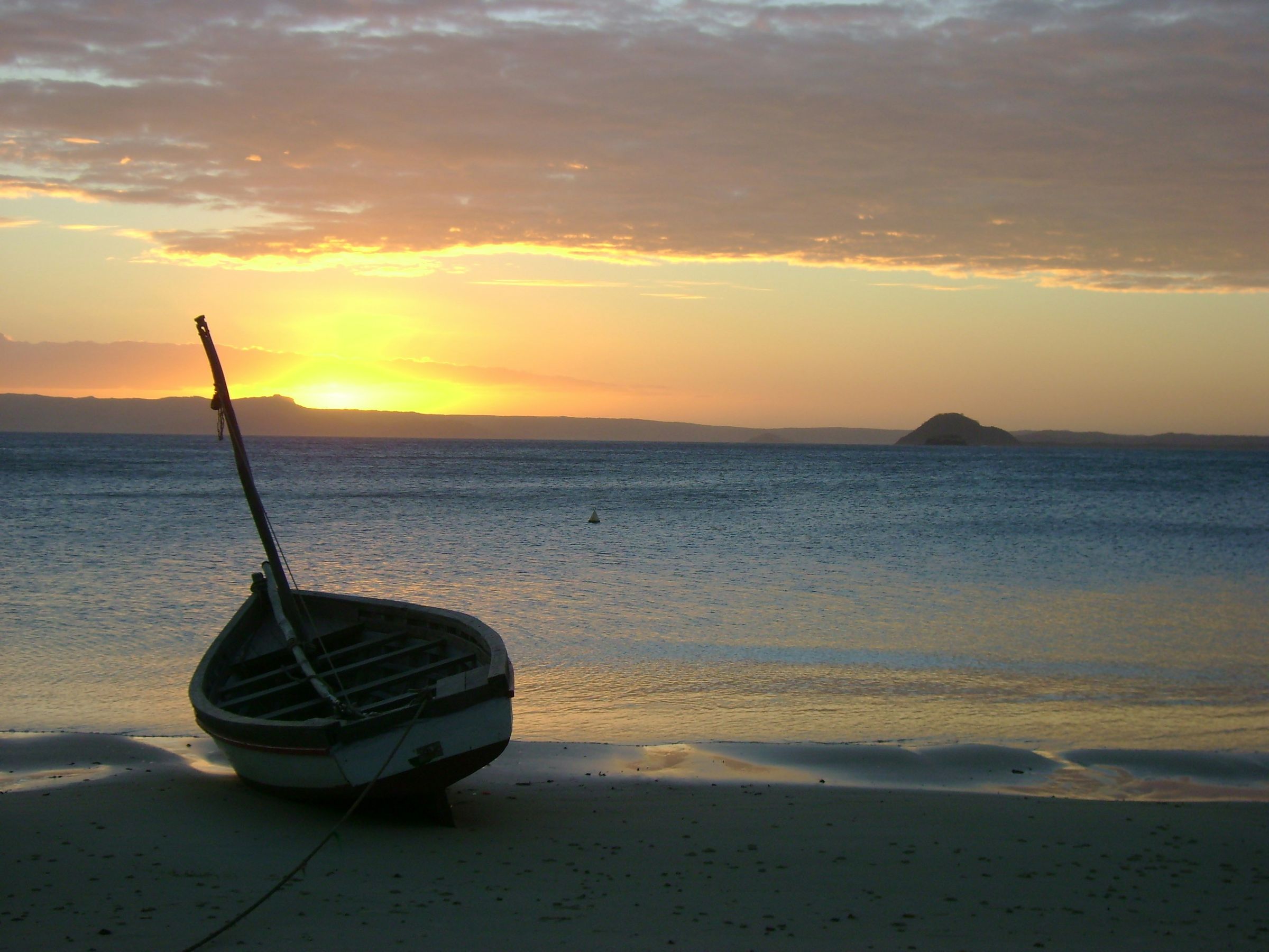 A wooden boat pulled up on a beach at sunset in northern Madagascar