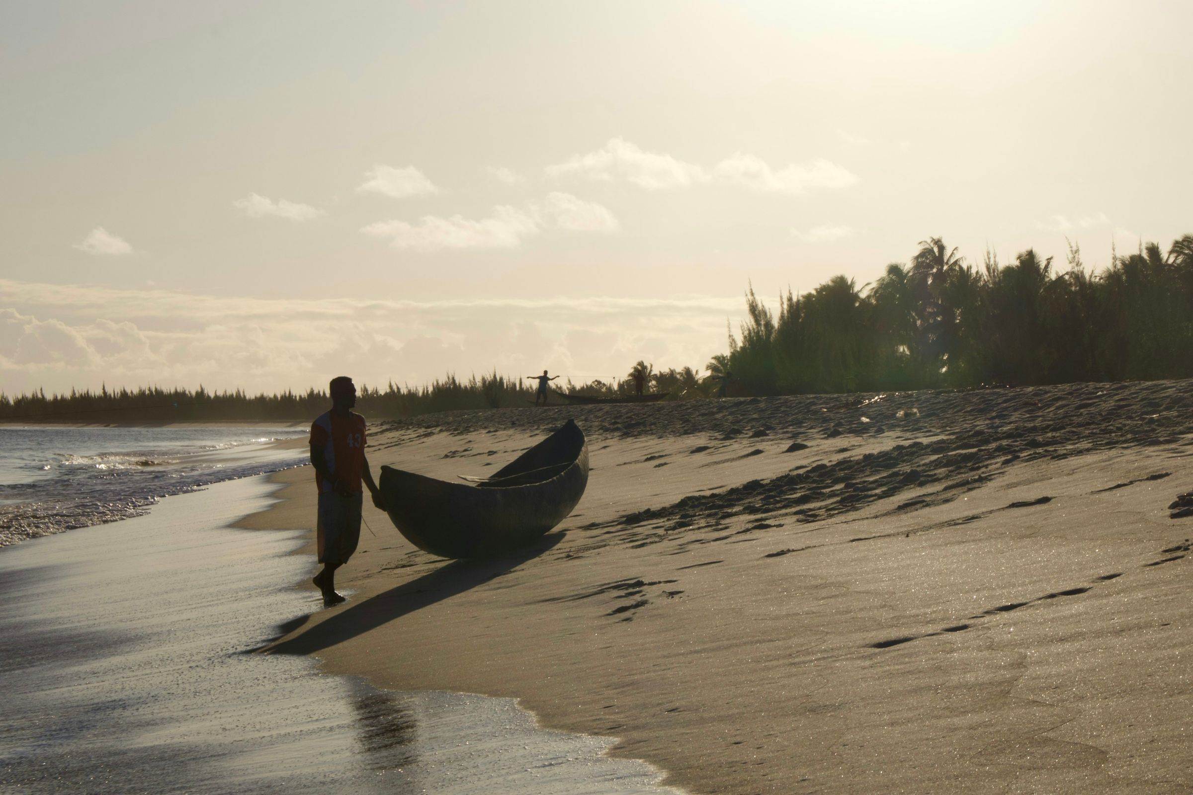 A fisherman pulling a pirogue up a beach in Madagascar