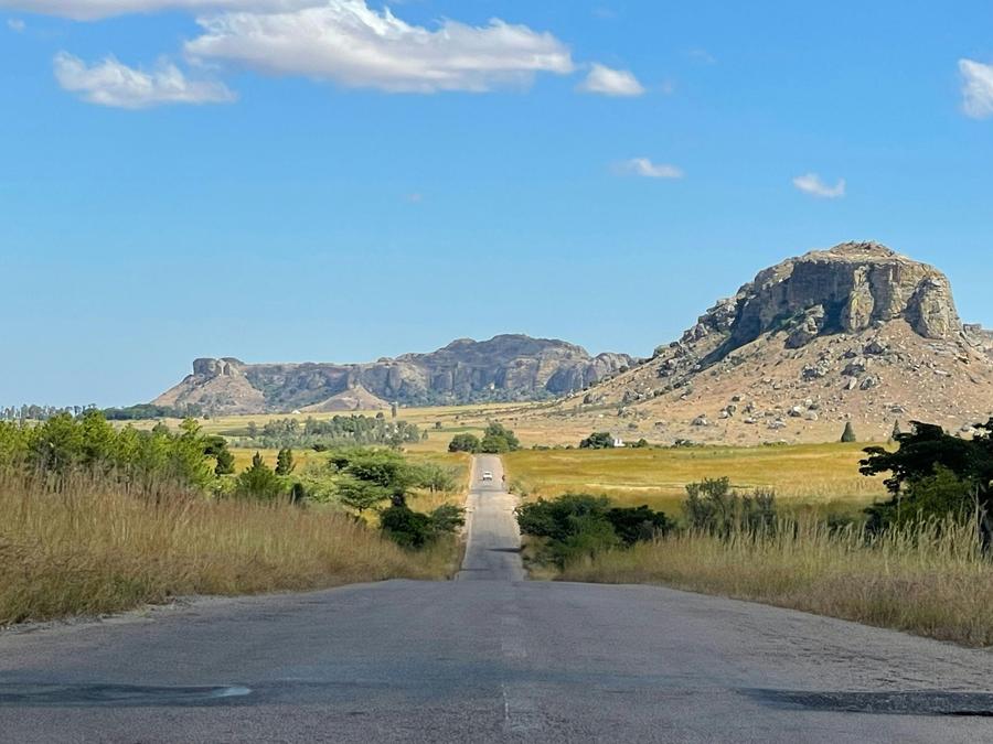 The RN7, almost empty, crossing golden grassland toward the sandstone massifs of Isalo