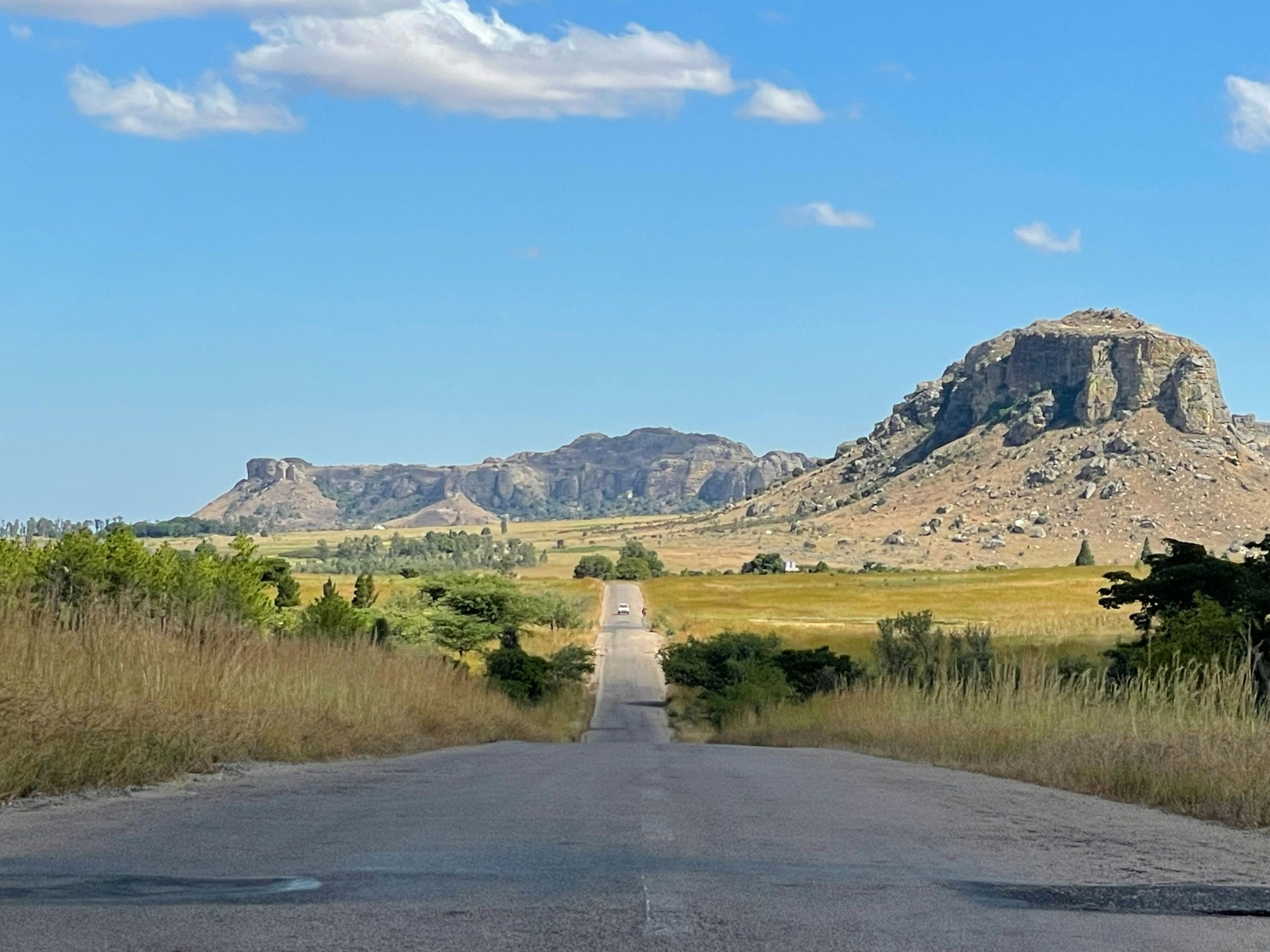 The RN7, almost empty, crossing golden grassland toward the sandstone massifs of Isalo