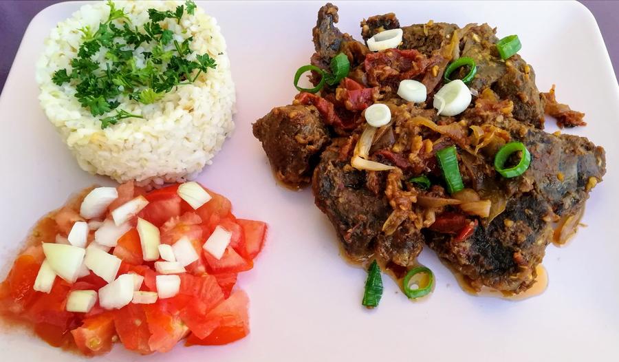 Malagasy plate of white rice, a meat stew with spring onions and diced tomato salad