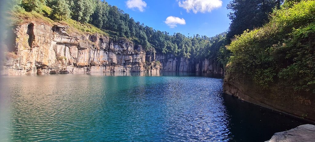 A turquoise crater lake below high cliffs