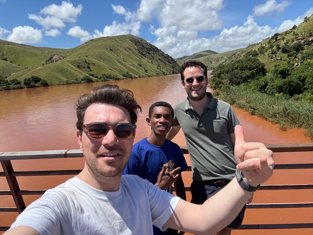Two travellers and their guide on a boat on a red river